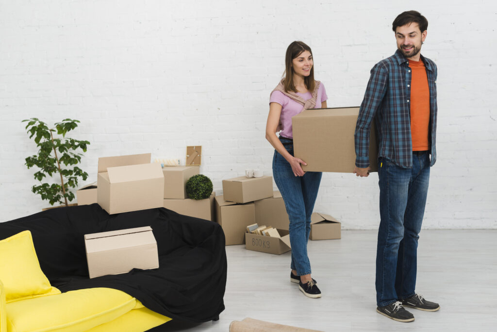 young couple holding cardboard box their new house